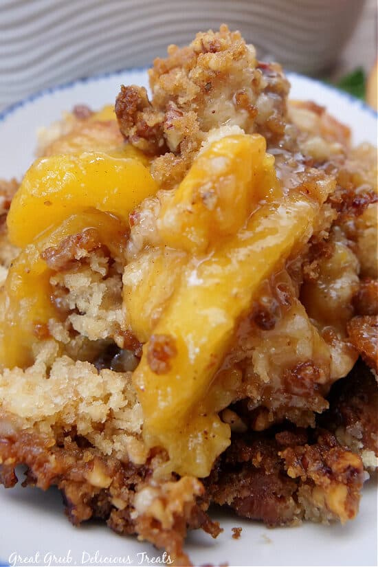 A close up photo of a serving of peach cobbler in a white bowl.