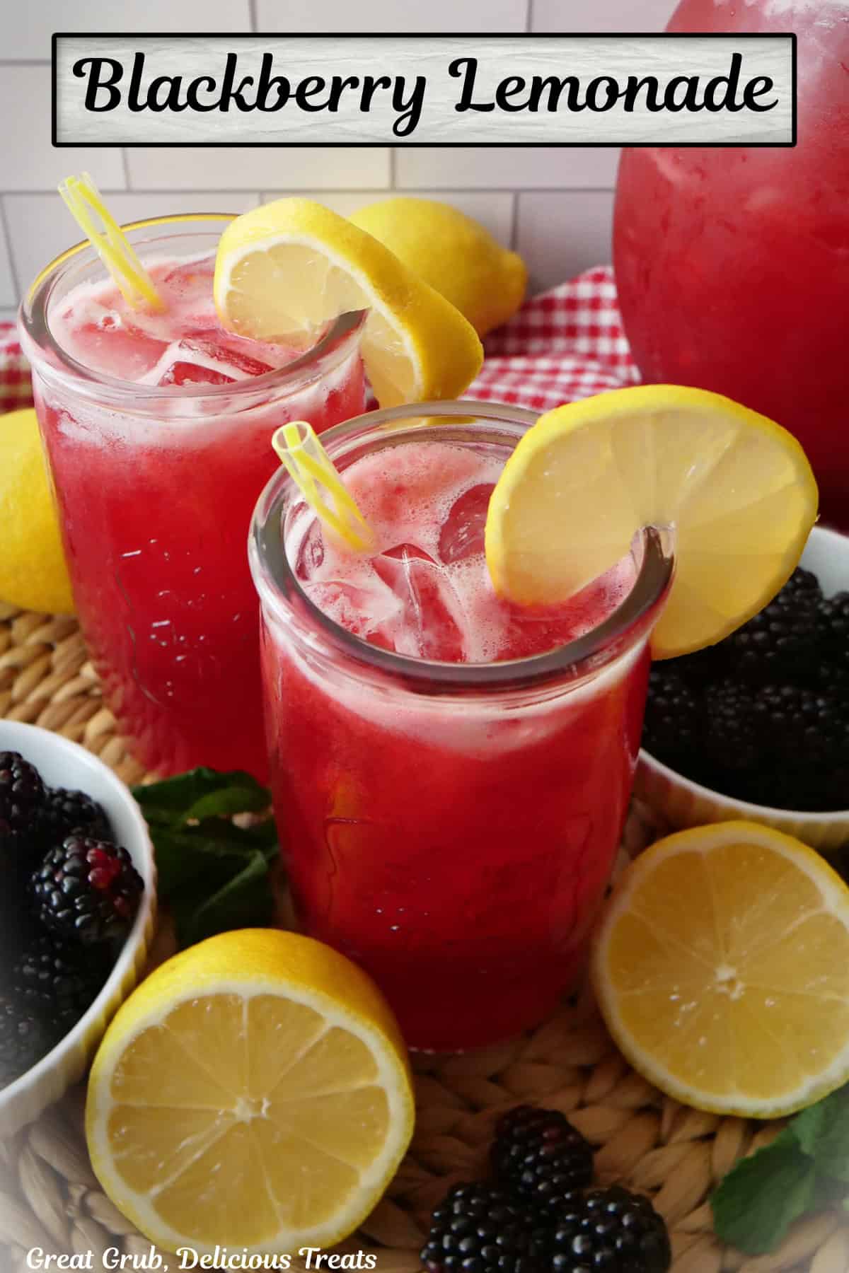 Two glasses and a picture of blackberry lemonade with fresh blueberries and lemon placed around them.