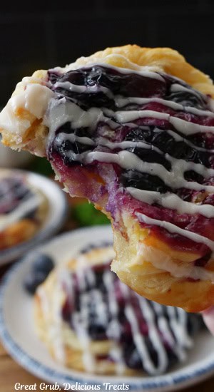 A close up of a blueberry danish with a few bites taken out of it.