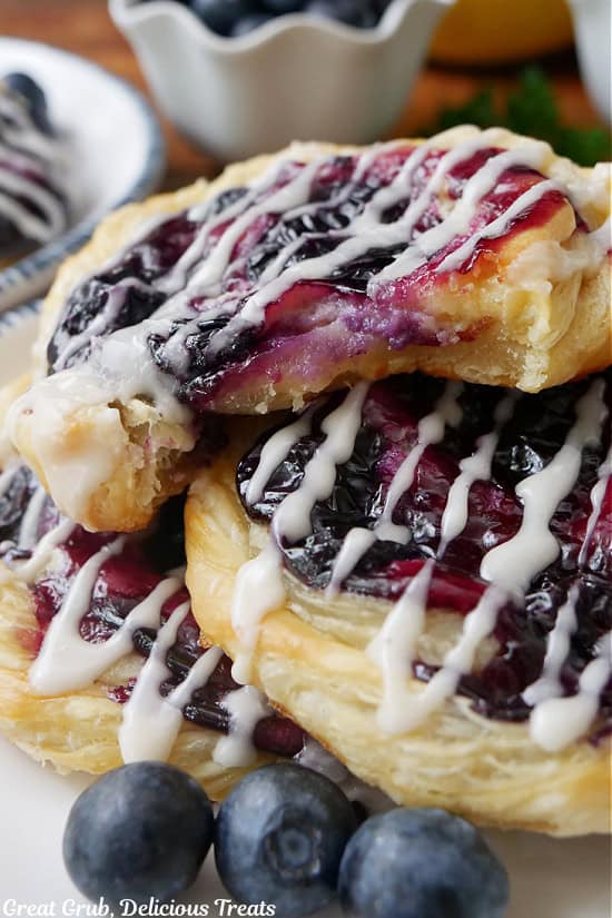 A close up of three blueberry danishes with a big bite taken out of one of the pastries.