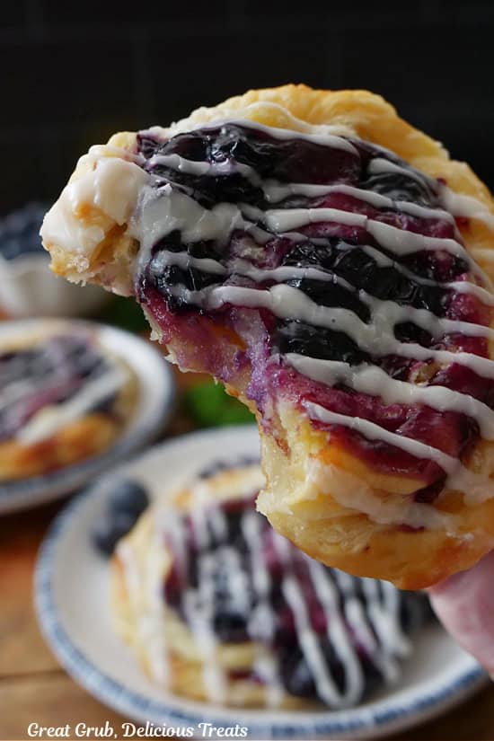 A close up of a blueberry pastry with a couple bites taken out of it.