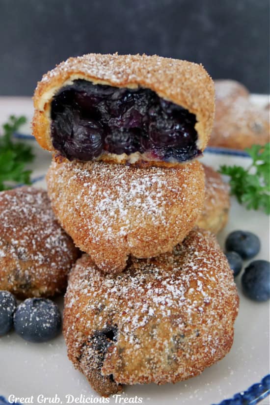 A stack of three blueberry pie bombs on a white plate with a bite out of the top one.