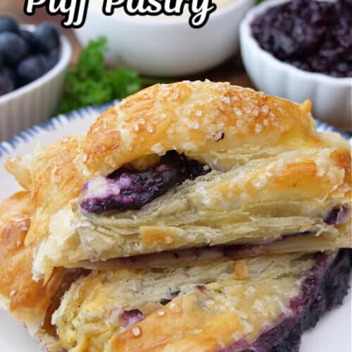 A white plate with three slices of flaky blueberry puff pastry on it.