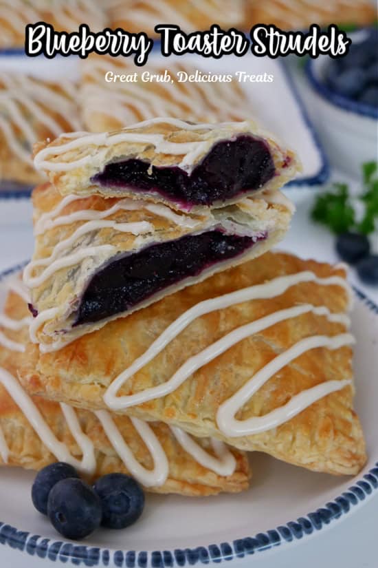 A round white plate with blue trim with three blueberry strudels on it with one cut in half.