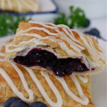 A couple blueberry toaster strudels on a round white plate with blue trim.