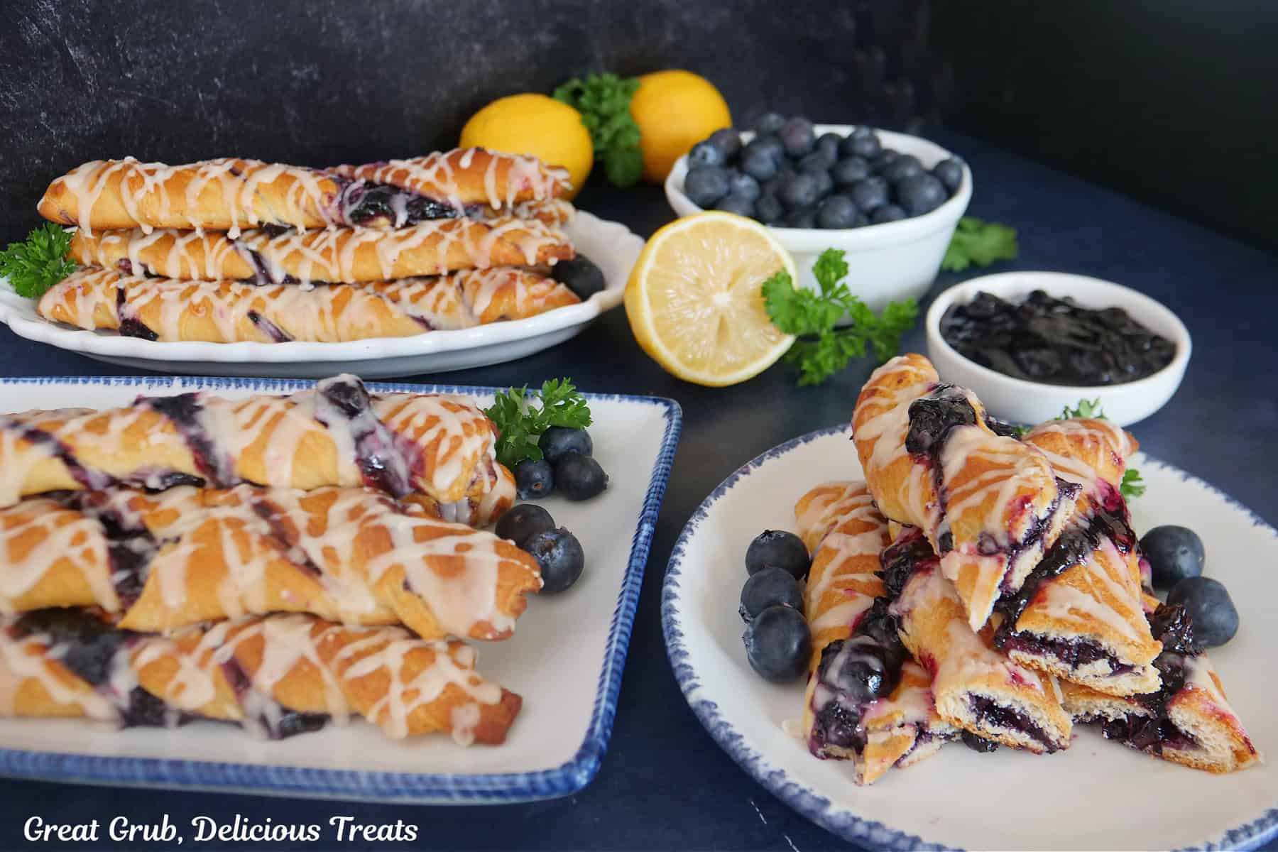A dark blue surface with white plates with blue trim with blueberry twists placed on all of them.