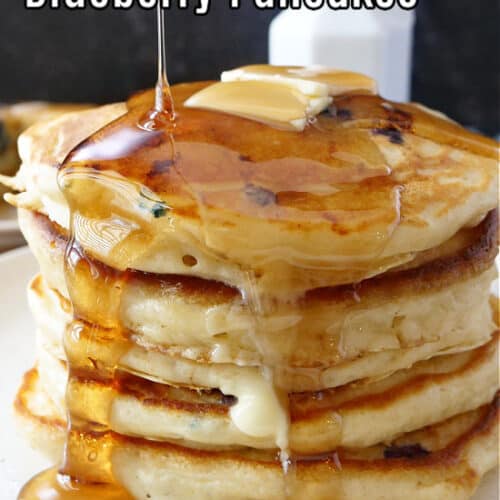 A stack of five pancakes topped with butter and maple syrup.
