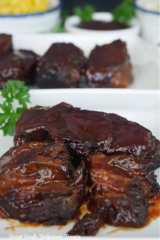 Two boneless barbecue beef ribs on a white plate.