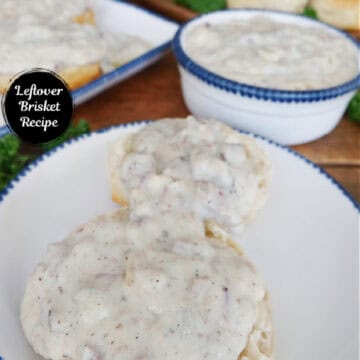 A round white plate with a two biscuits covered with southern brisket gravy.