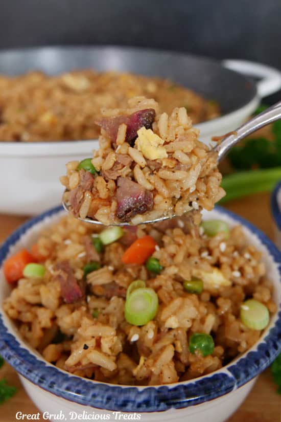 A spoonful of brisket fried rice held above a bowl full of fried rice.