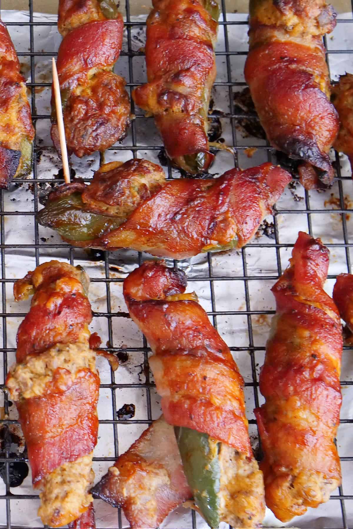 A wire rack on a baking sheet with baked brisket stuffed jalapenos on it.