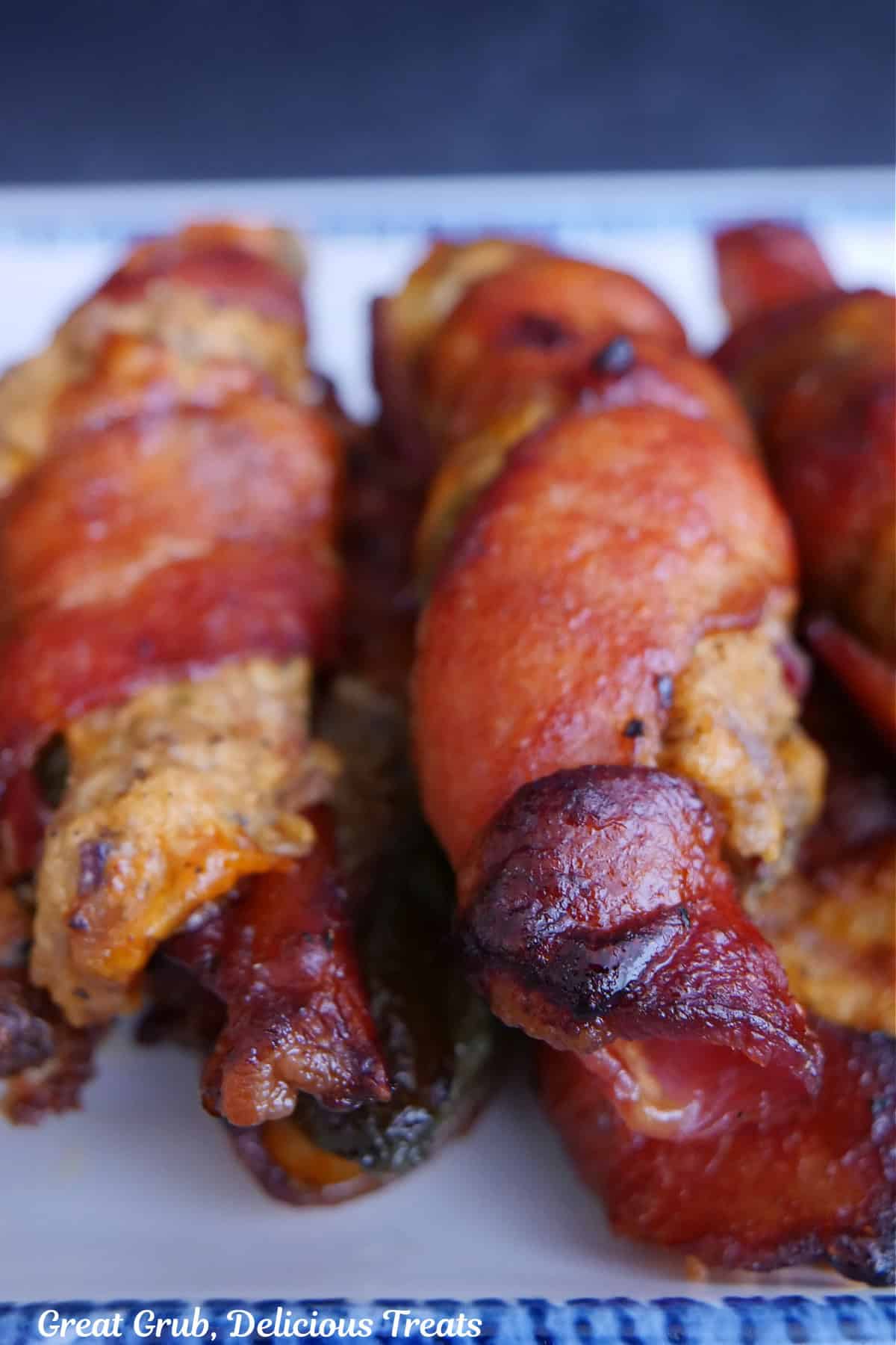 A small stack of baked bacon wrapped brisket stuffed jalapenos on a white plate.