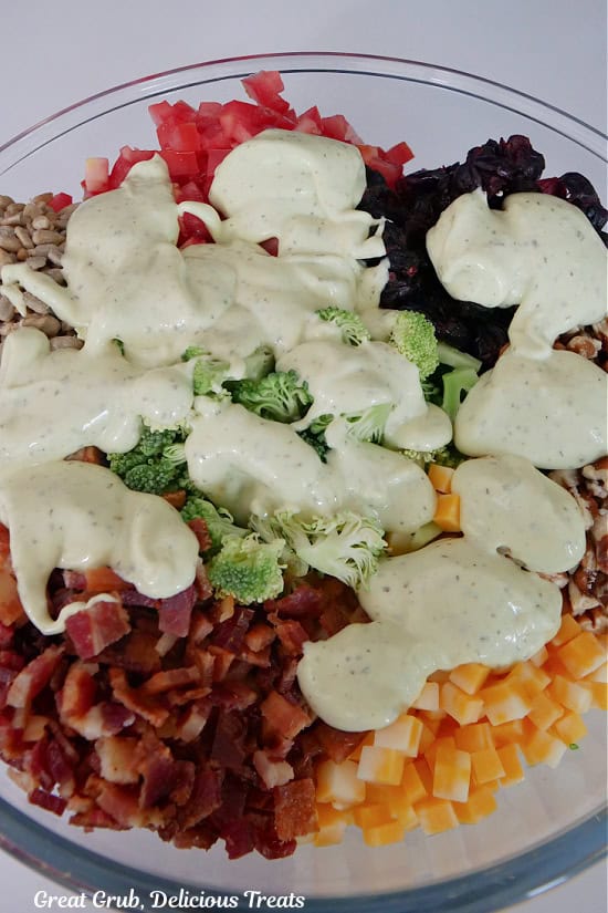 A glass bowl with all the ingredients for broccoli salad plus the avocado lime ranch dressing.