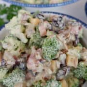 A serving of broccoli salad in a white round bowl with blue trim.
