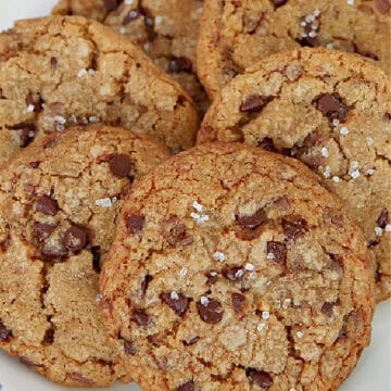 A round white plate with blue trim with six cookies on it.