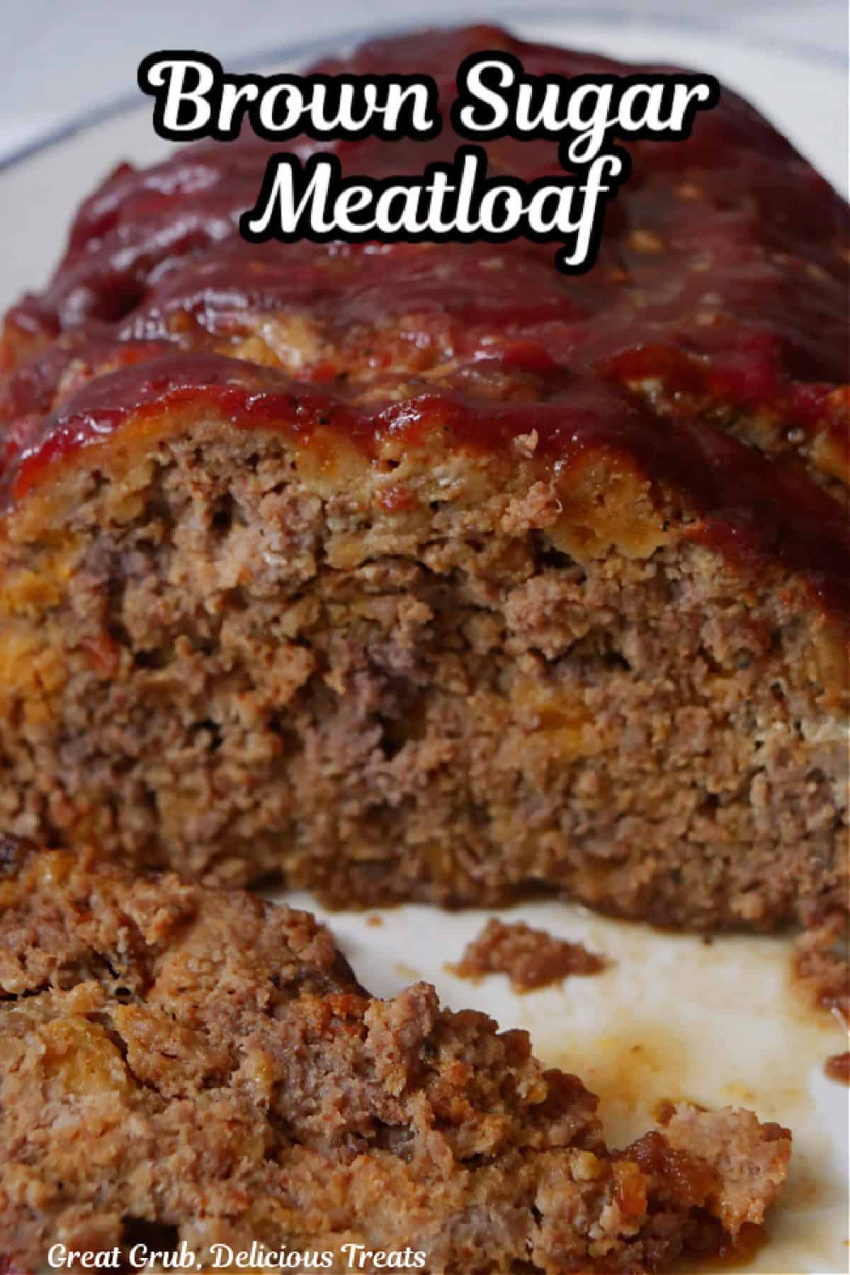 A white plate with meatloaf on it with a few slices removed.