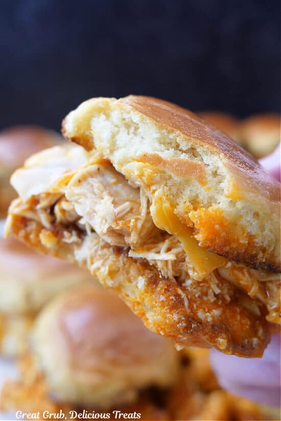 A close up of a handheld chicken slider with a bite taken out of it.
