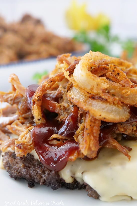 Bunless Burgers are the best way to use leftover pork, especially when carb conscious. A close up photo of pulled pork piled on top of a cheeseburger patty and drizzled with BBQ sauce.