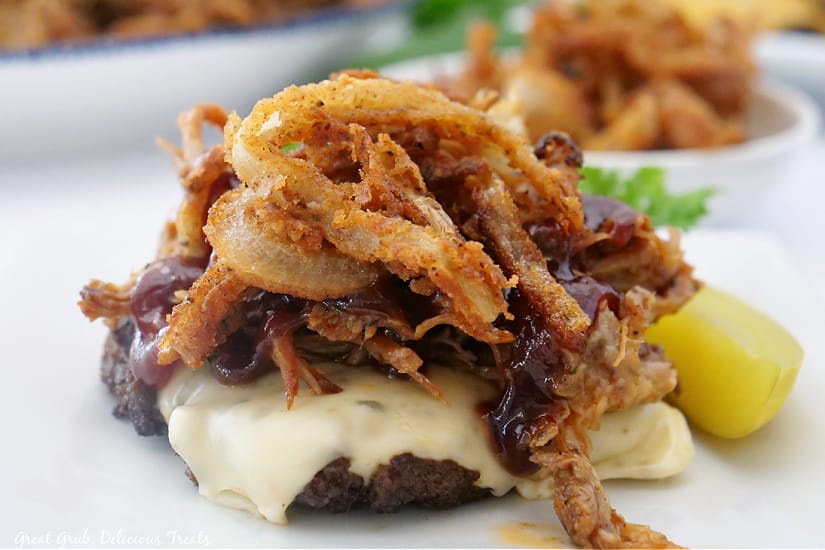 Bunless Burgers are delicious and hearty burgers that are topped with pulled pork and BBQ sauce. A landscape photo of a burger with cheese, pulled pork, and fried onion strings.