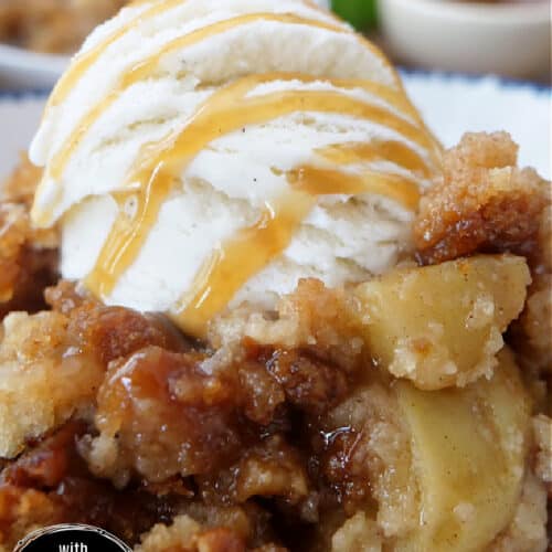 A white bowl with blue trim with a serving of caramel apple cobbler and a scoop of vanilla ice cream in it.
