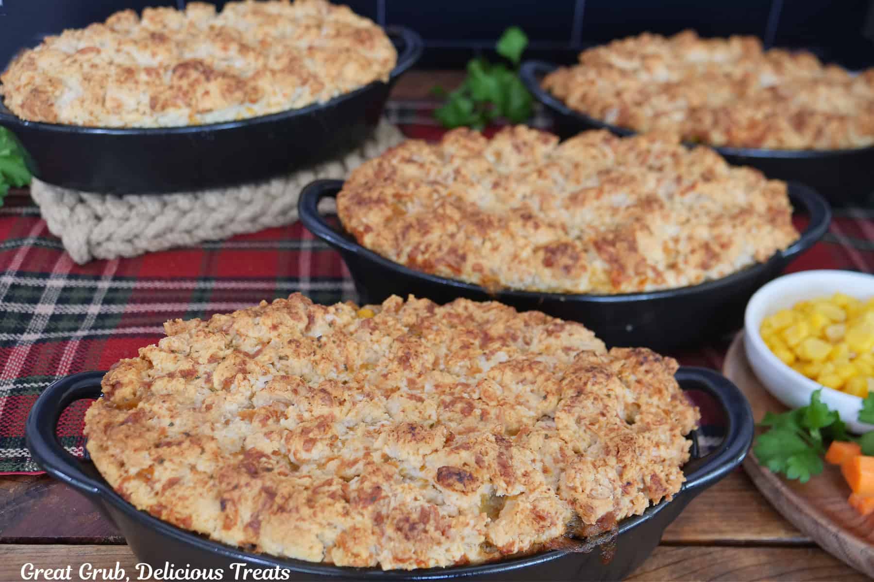 Four black oval baking dishes with cheddar bay cheesy beef pot pies in them.