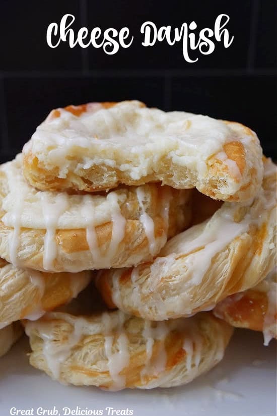A stack of cheese Danishes on top of each other with a bite taken out of the top pastry.
