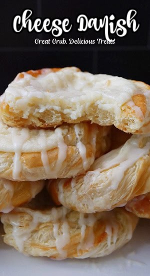 A stack of cream cheese danishes with a bite taken out of the top danish.