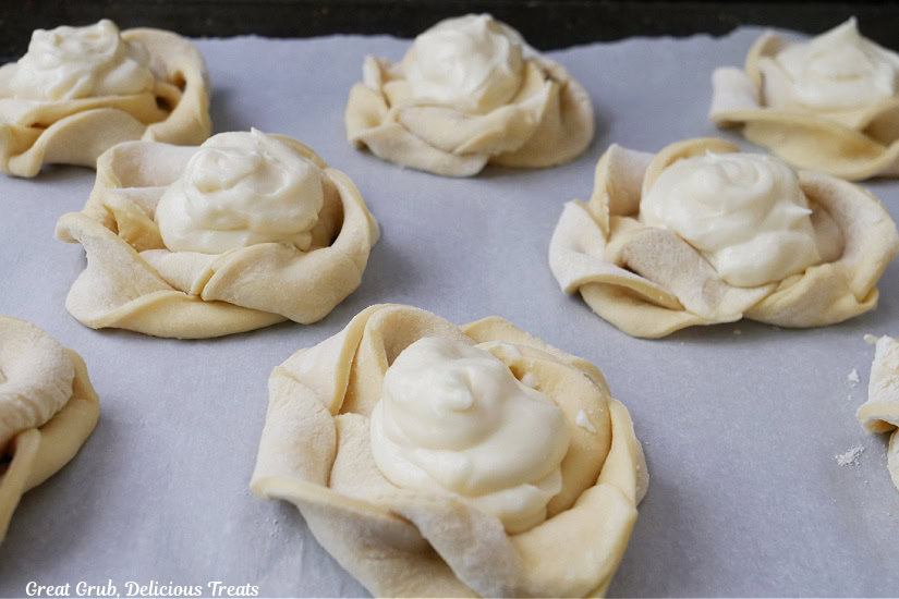 A baking sheet with twisted pinwheels and cheese filling on it right before going into the oven.