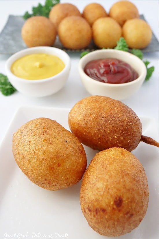 Cheese Bites is a simple recipe made with only ten simple ingredients that are surely to already be in your pantry. A small white plate with three cheese bites on it and a silver plate filled with some in the background.