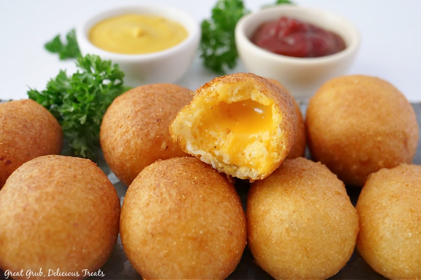 Cheese Bites are a delicious and cheesy snack or appetizer that is perfect to make for any occasion. A large tray with cheese bites on it with two small bowls of ketchup and mustard.