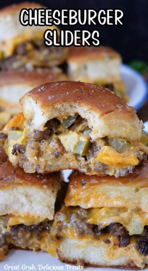 Three cheeseburger sliders on a white plate with a bite taken out of one of the sliders.