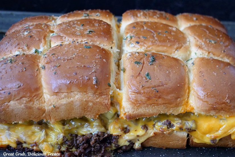 Twelve sliders on a baking sheet after being pulled out of the oven.