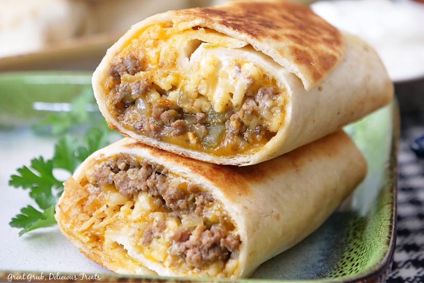 Two halves of a burrito on a green and white plate.