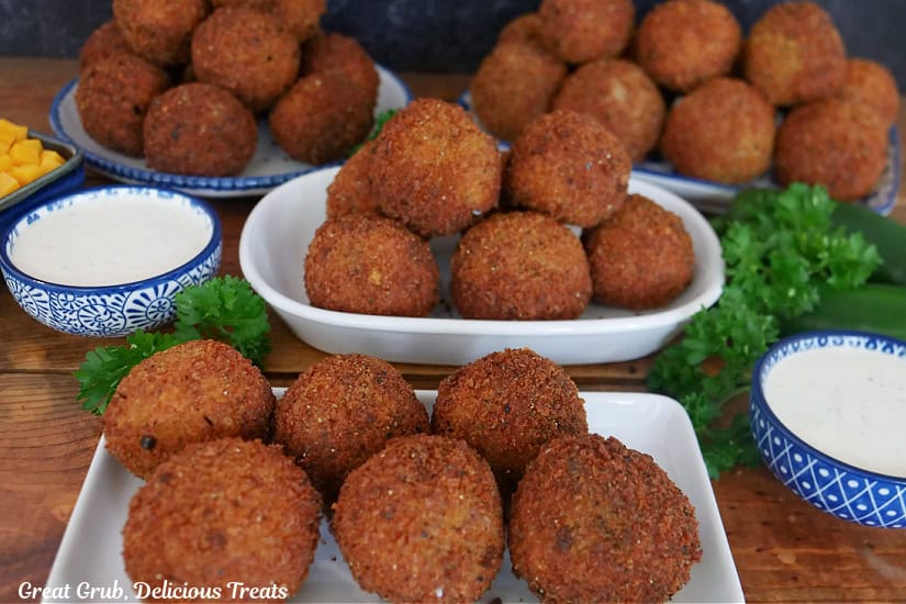 A wood surface with white plates filled with crispy ground beef balls.