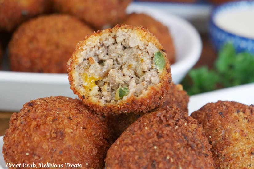 A close up photo of ground beef balls with a bite taken out of one of them.