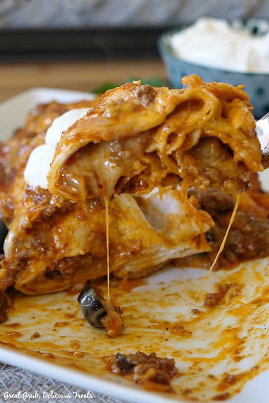 Cheesy Ground Beef Enchiladas are cheesy, full of ground beef and seasoned perfectly. A bite of ground beef enchilada on a fork lifted up off the plate.
