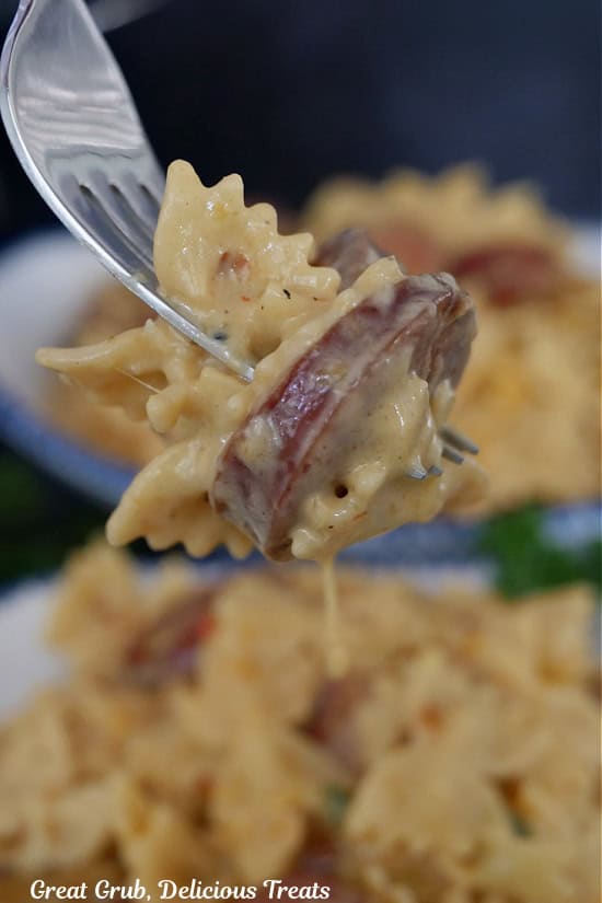 A bite of cheesy sausage and pasta on a fork.