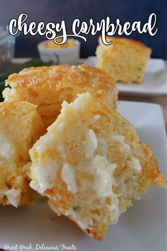 A white plate with a piece of cornbread cut in half and lathered with butter.
