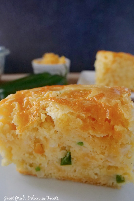 Cheesy Cornbread is dense, filling, and delicious and is loaded with diced jalapenos and shredded cheese. A close up photo of a piece of cornbread where you can see the diced jalapeno and onion, and the cheese baked on top.