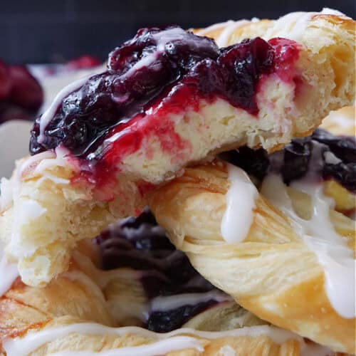 A close up of three cherry pastries with a few bites taken out of the top pastry.