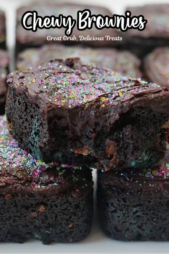 Three chewy brownies on a white plate with a bite taken out of the top brownie.