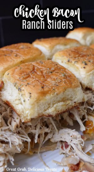 A white plate with shredded chicken sliders on it.