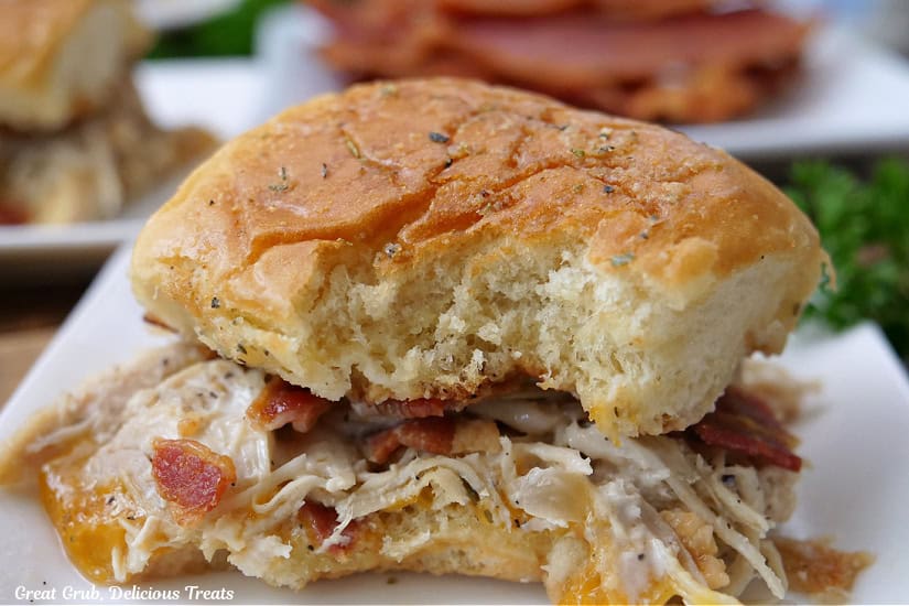 A horizontal photo of a small white plate with a chicken slider on it.
