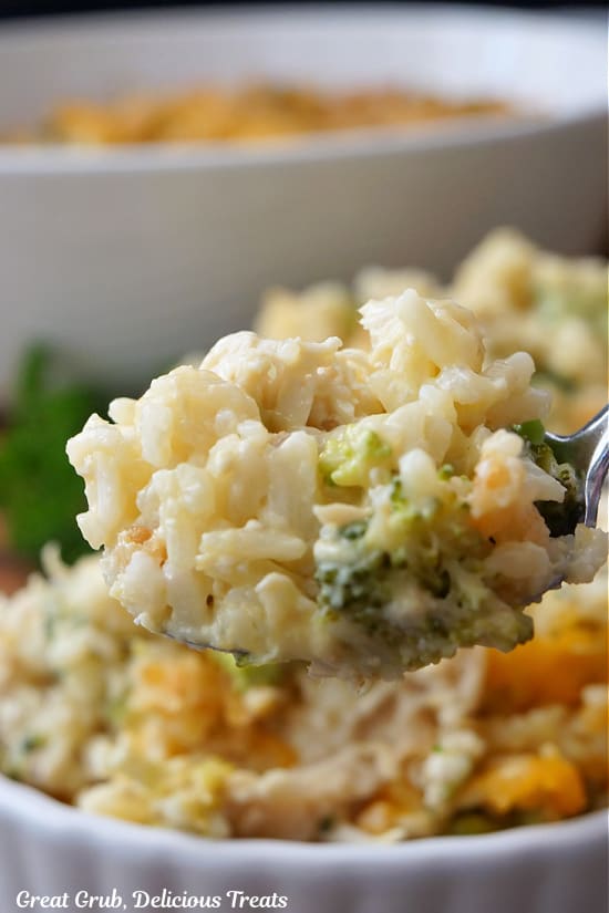 A close up of a spoonful of cheesy rice and broccoli with chicken.