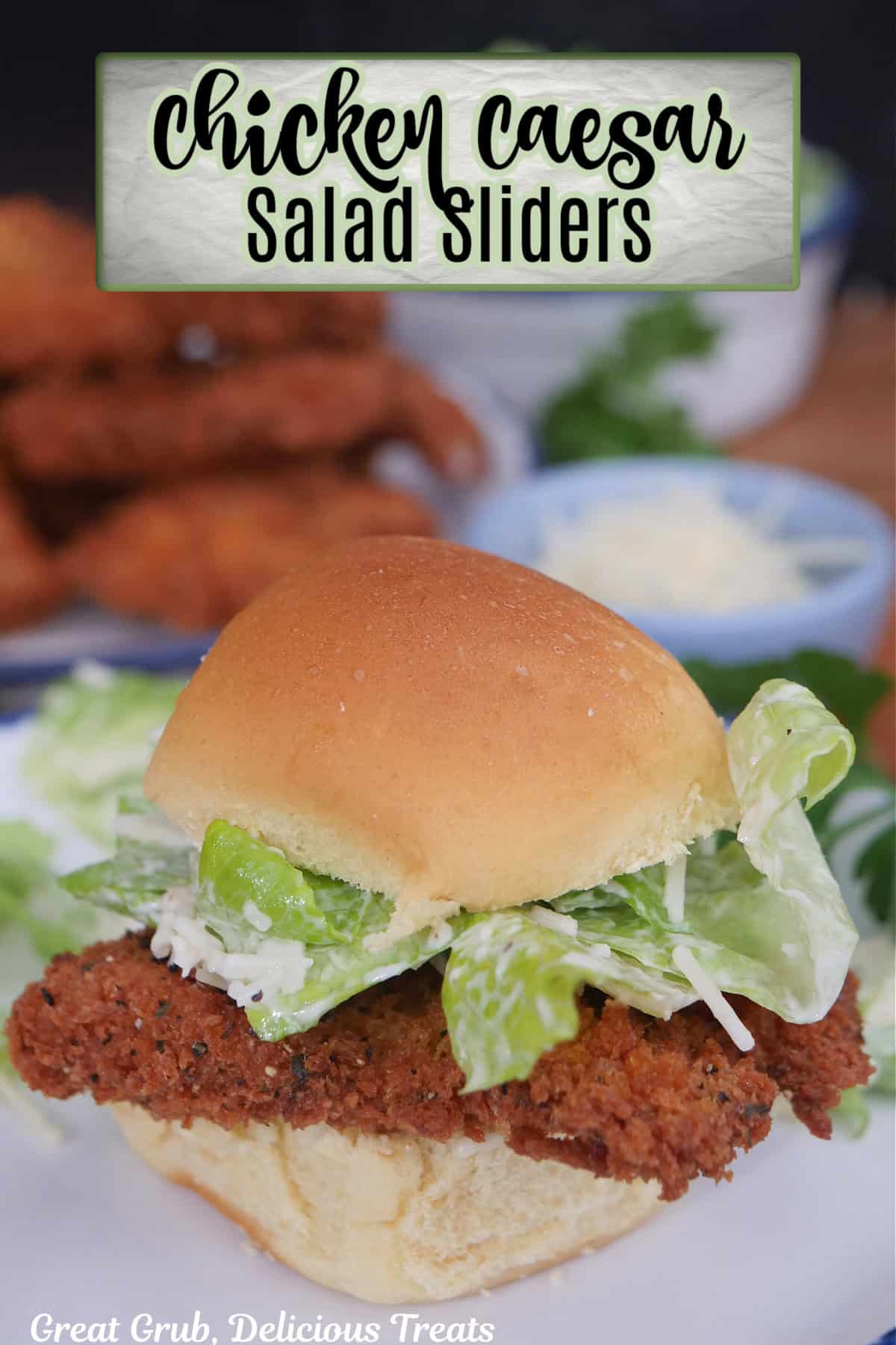 A chicken caesar salad slider on a white plate with a slider bun, fried chicken, and caesar salad with the title overlay at the top.