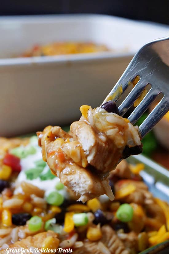 A close up of a bite of chicken with rice on a fork.