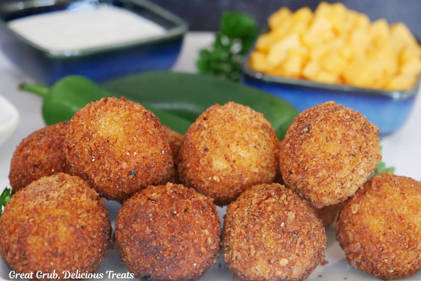 A white plate with ten fried chicken jalapeno cheese bites on it.