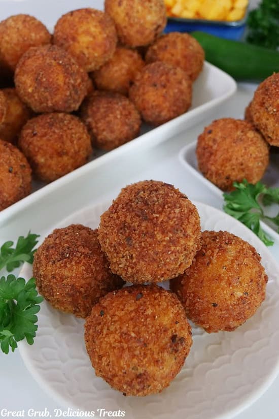 A small white plate with 5 chicken cheese bite on it with additional bites in the background.