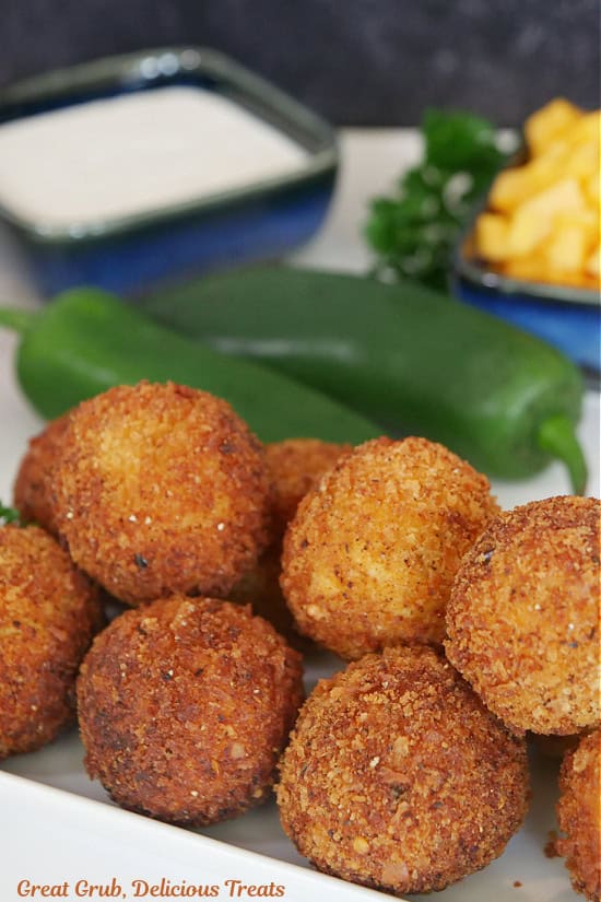 A stack of crispy deep fried chicken cheese bites on a white plate.