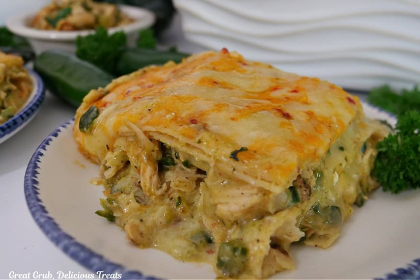 A white round plate with blue trim with a serving of enchilada casserole on it.